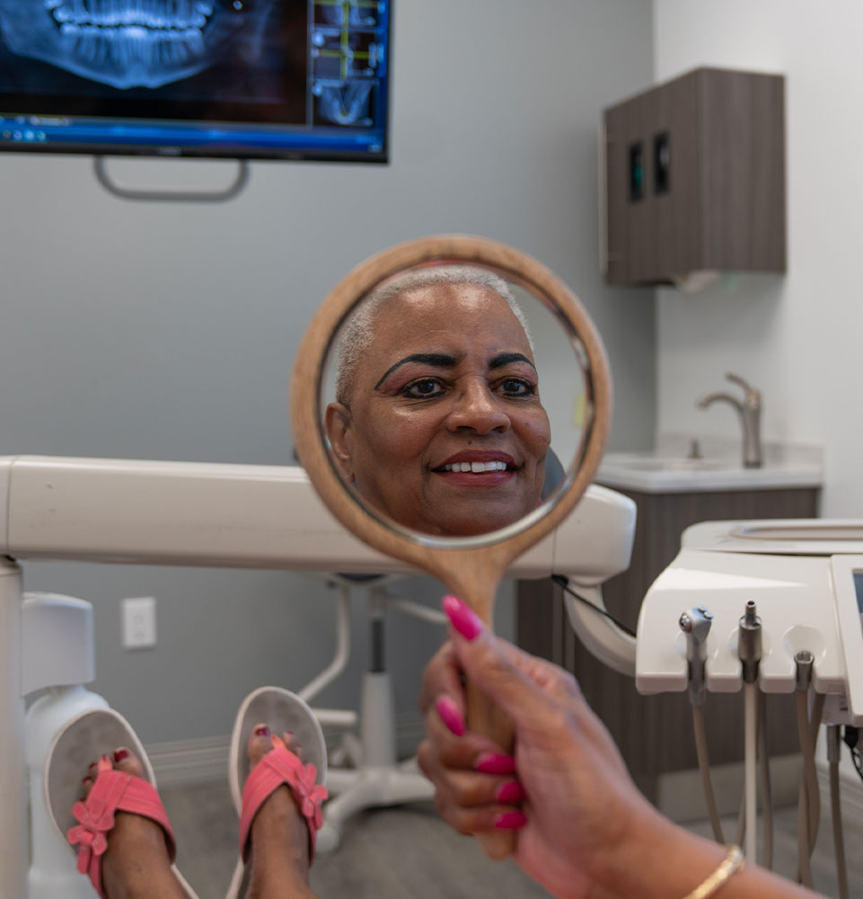 patient smiling brightly while looking in the mirror after their dental treatment