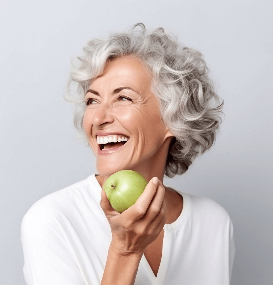 Beautiful cheerful smiling mature woman bites a green apple.