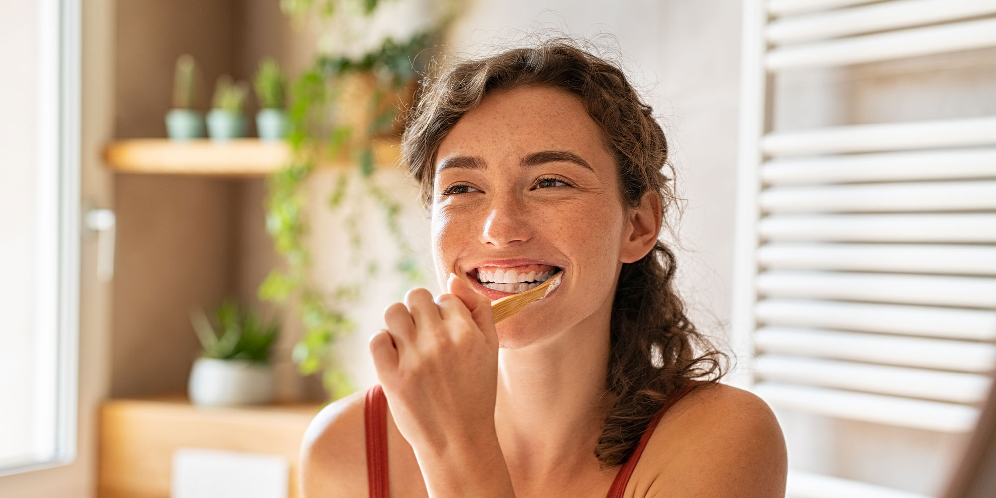 Woman brushing teeth at mirror within their bathroom