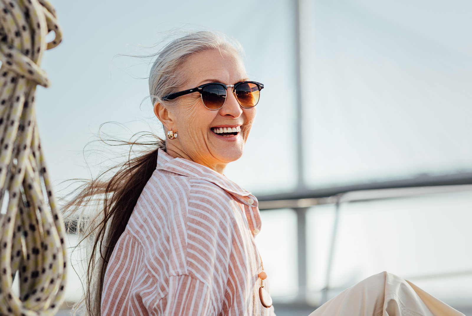 Laughing mature woman wearing sunglasses and looking at camera. Smiling female in casuals enjoying vacation.