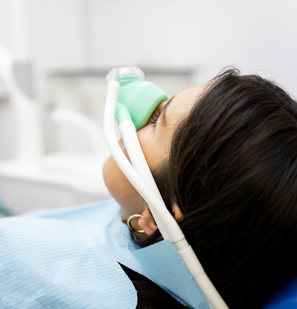 adult woman sits in a dentist's clinic wearing a nasal mask to inhale nitrous oxide