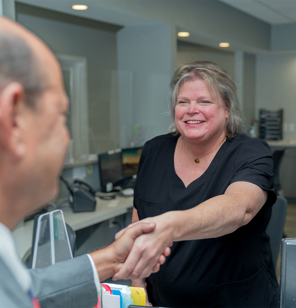 staff member shaking hands with patient and smiling brightly after treatment