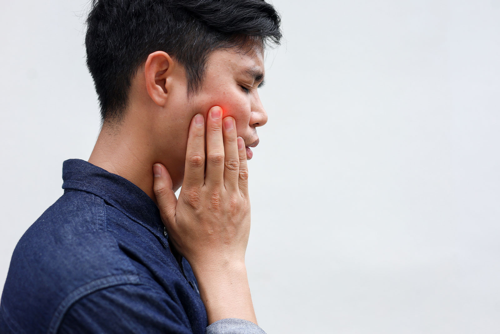 close up young asian man frown and use hand to massage on cheek after feeling pain or hurt from tmj muscle symptom