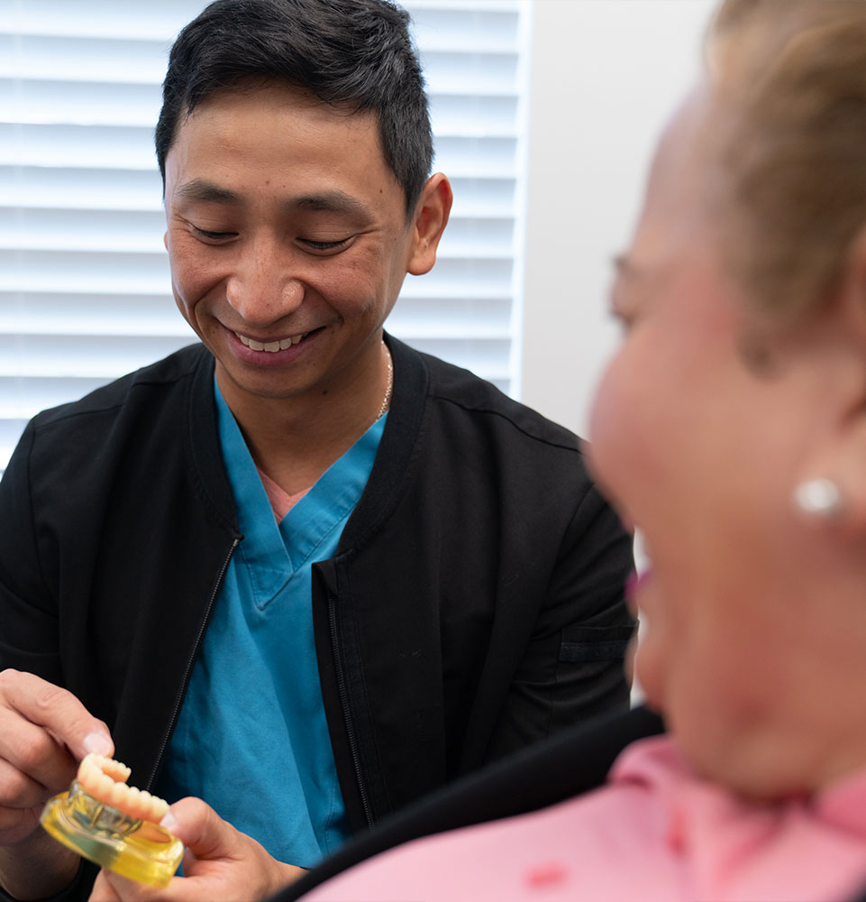 Team member showing Patient a model of dental implants